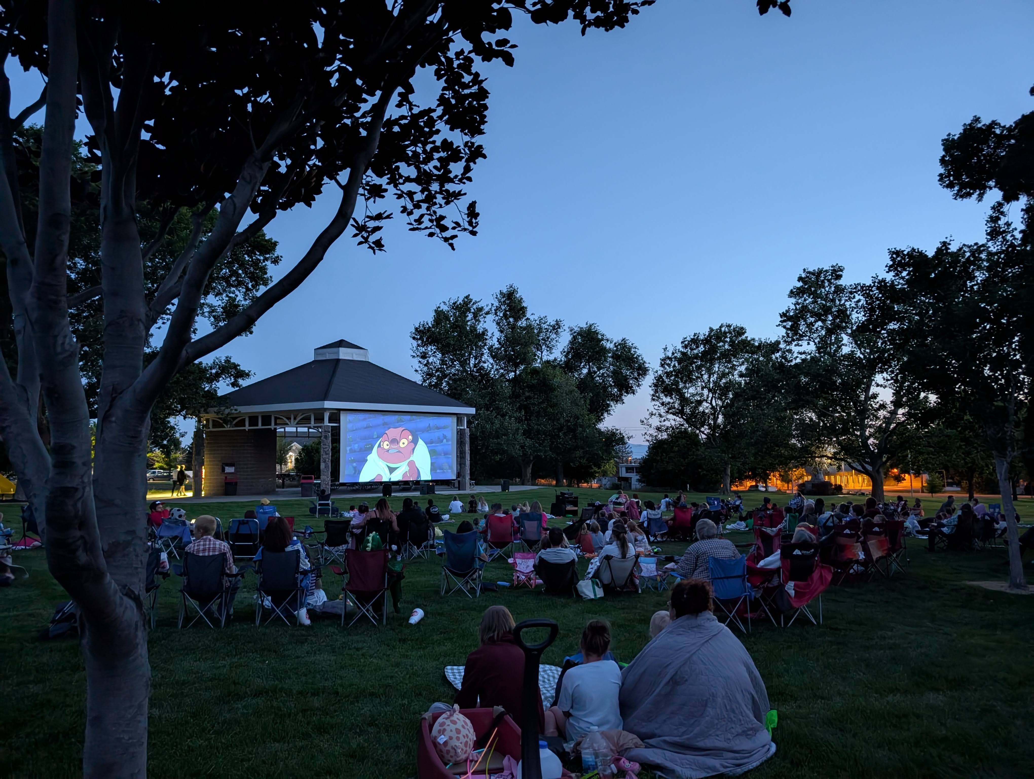 Crowd watches an outdoor movie as twlight decends on a summer eve