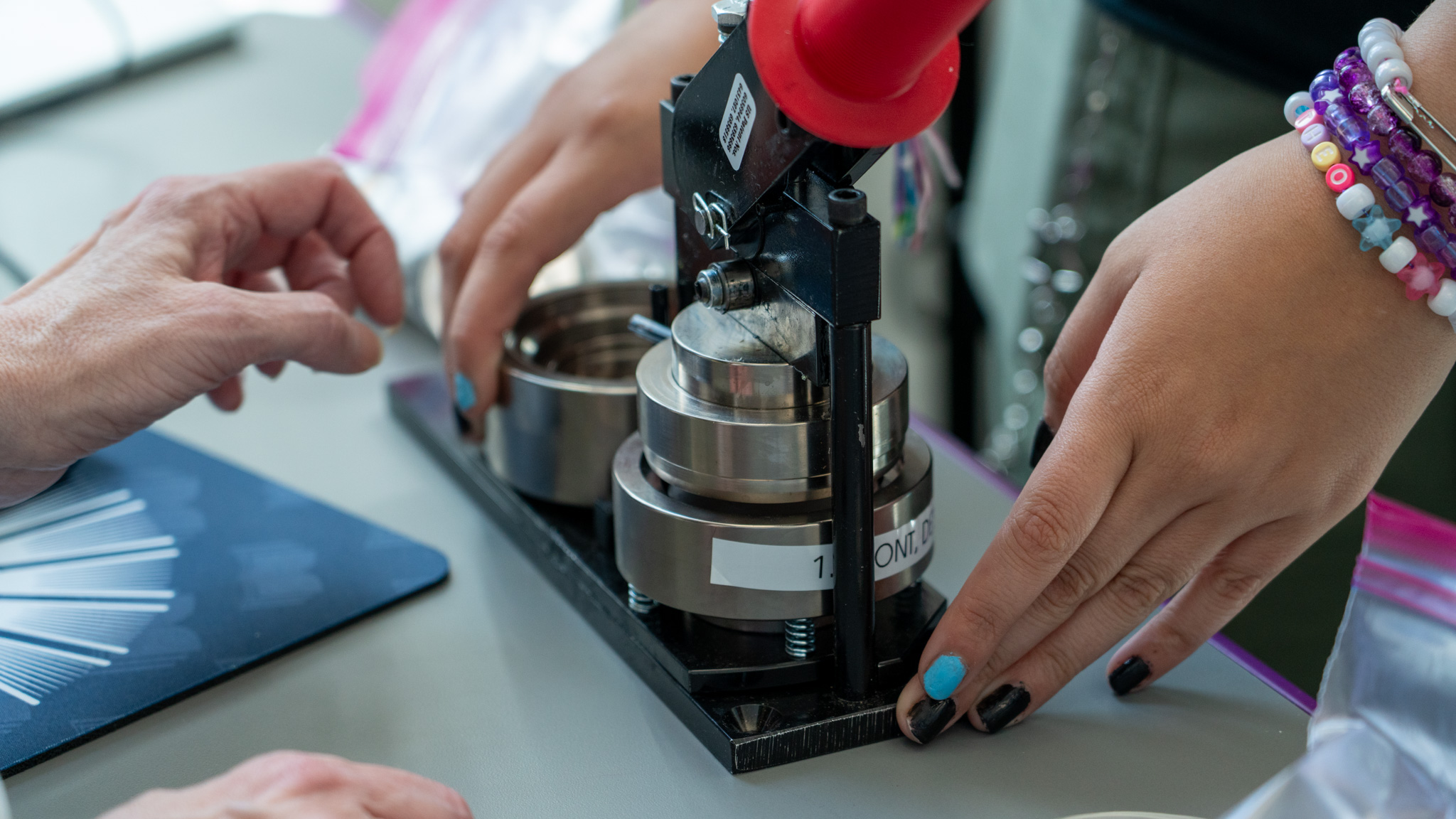 Hands using a button maker machine.