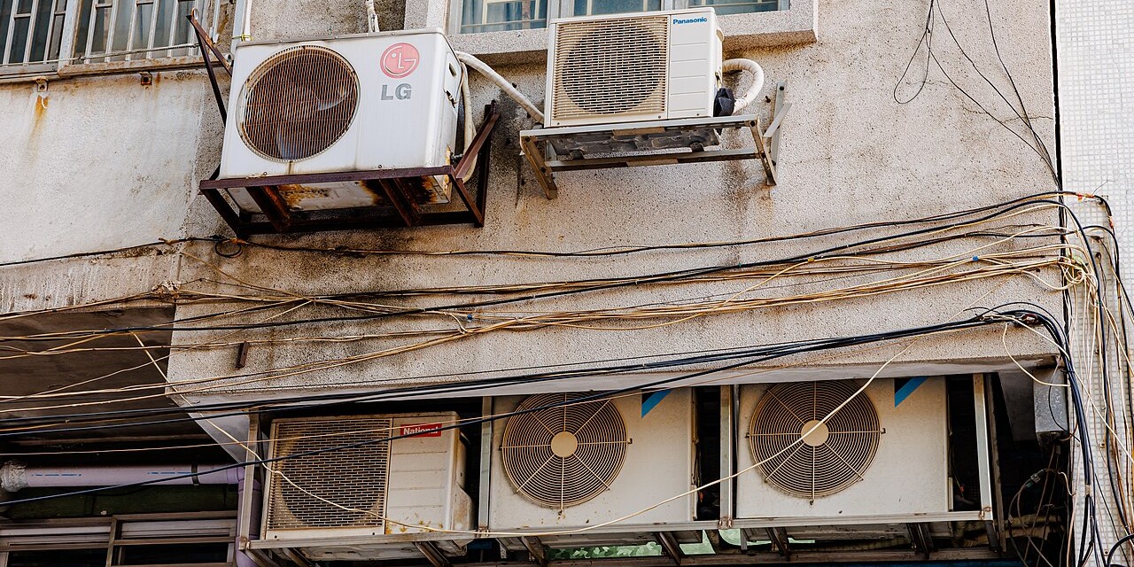 Several window air conditioning units on an apartment building.