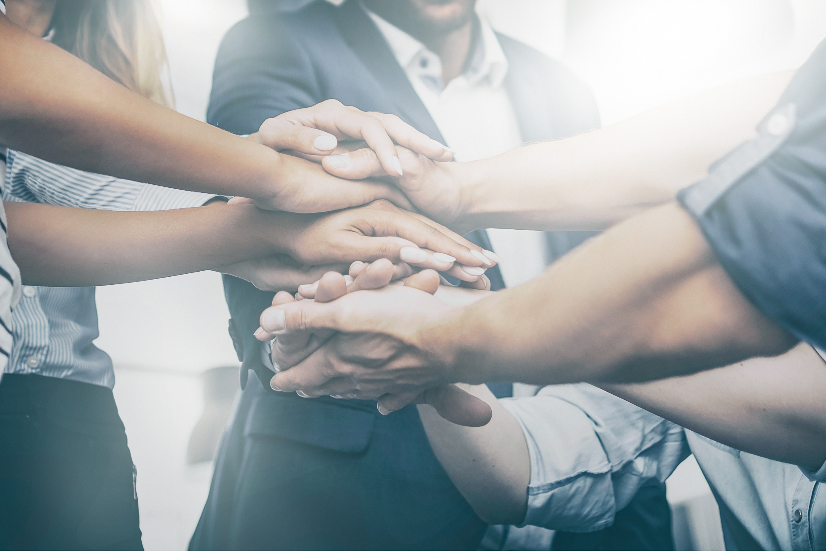 a group of people stacking their hands together while in a huddle