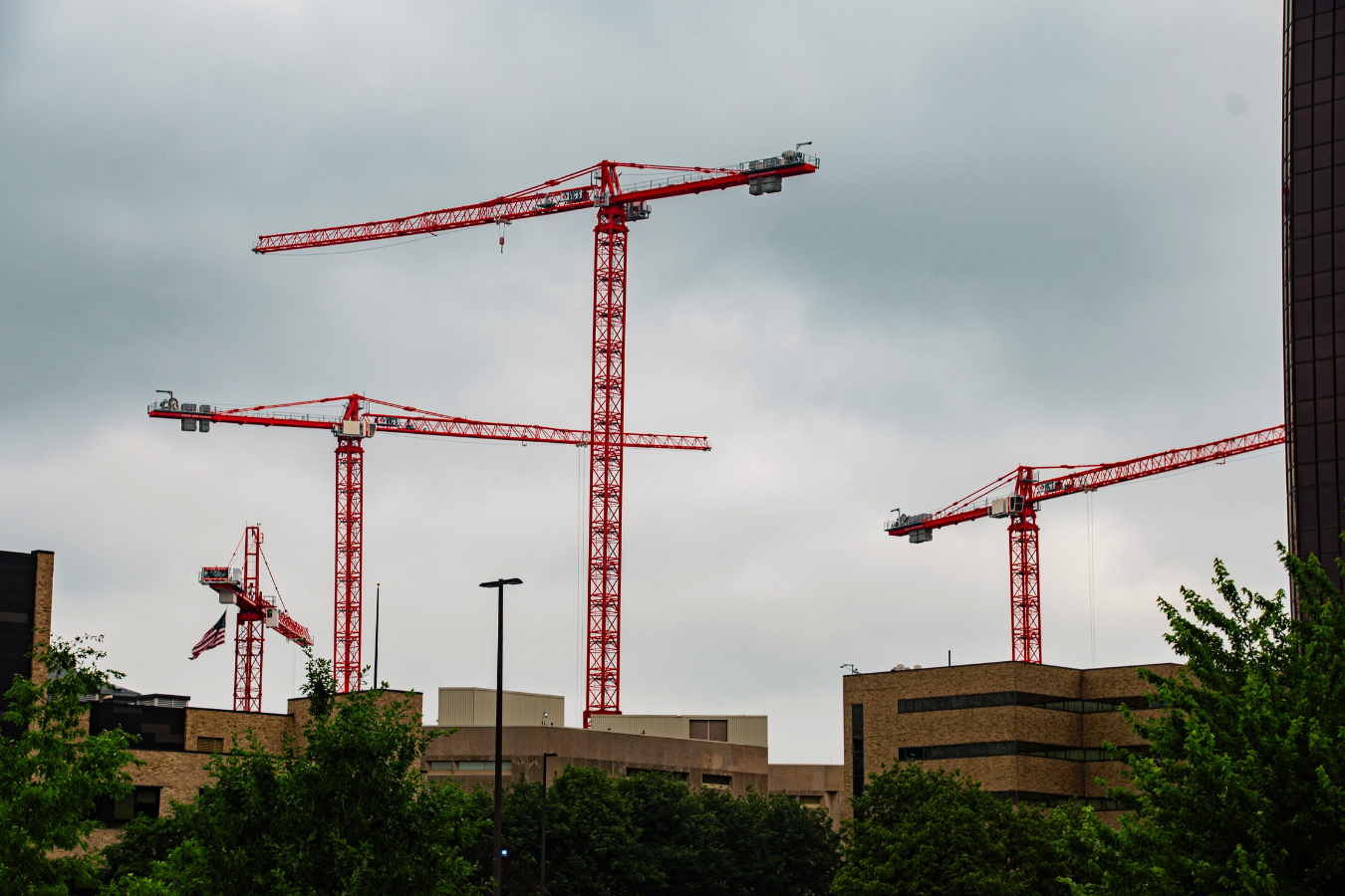 Four cranes suspended in the air above downtown buildings